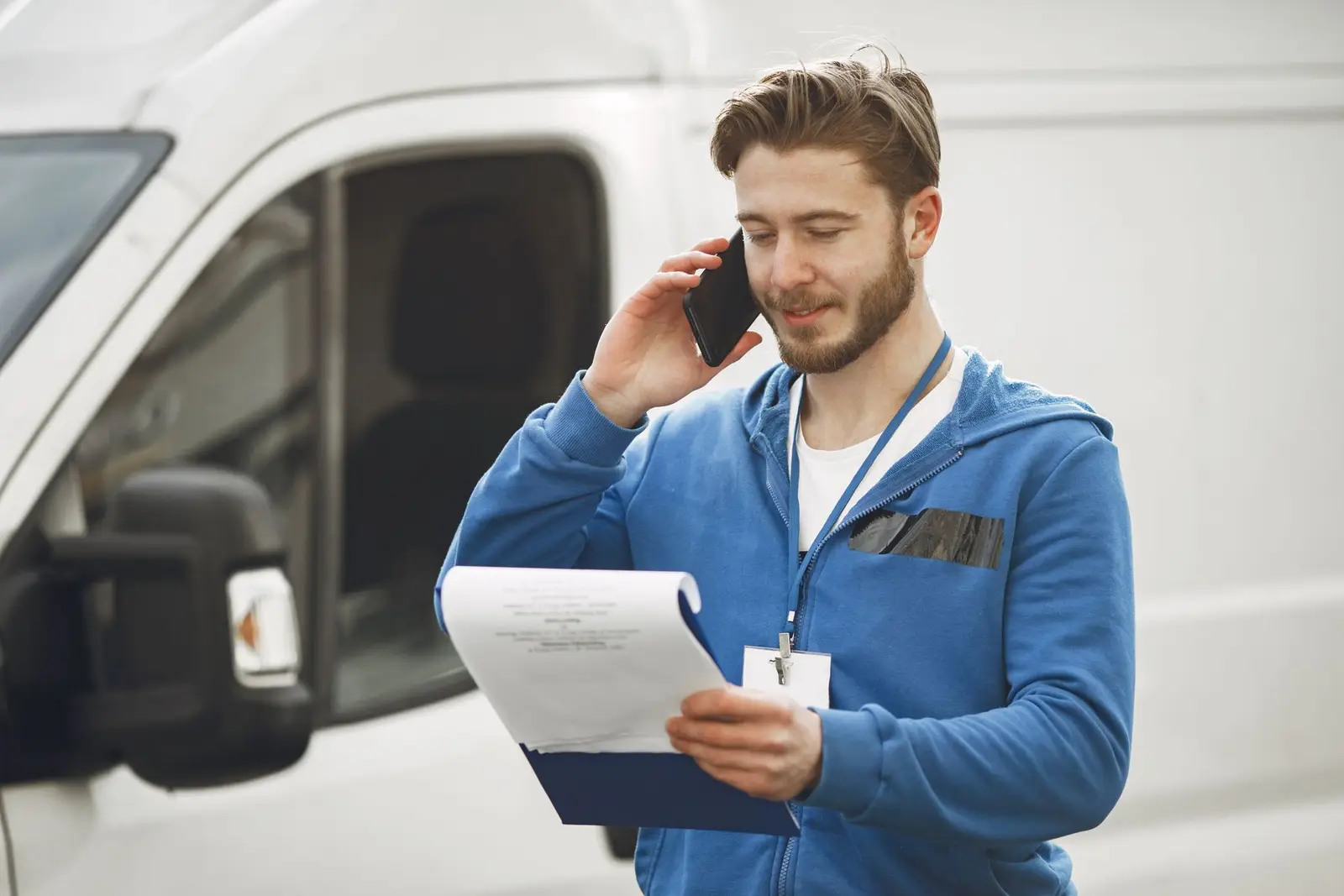 Professionnel utilisant son téléphone devant son utilitaire