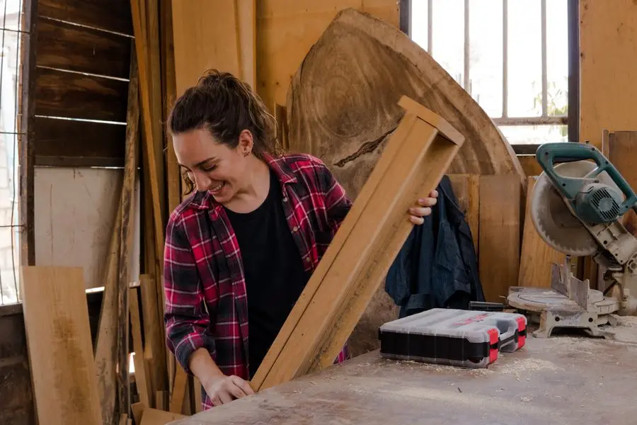 Menuisière travaillant une pièce de bois dans son atelier
